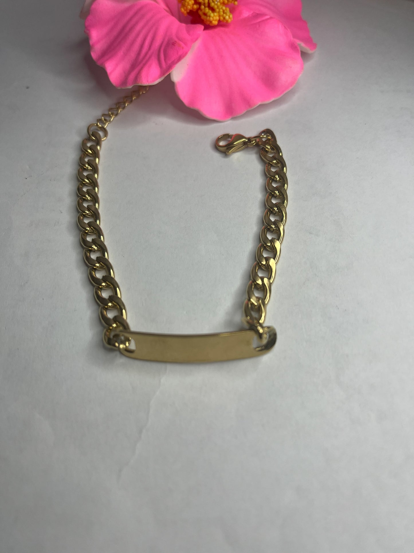 Bracciale Golden Thread sottile placcato oro con maglia fine delicata su sfondo grigio con petali rosa