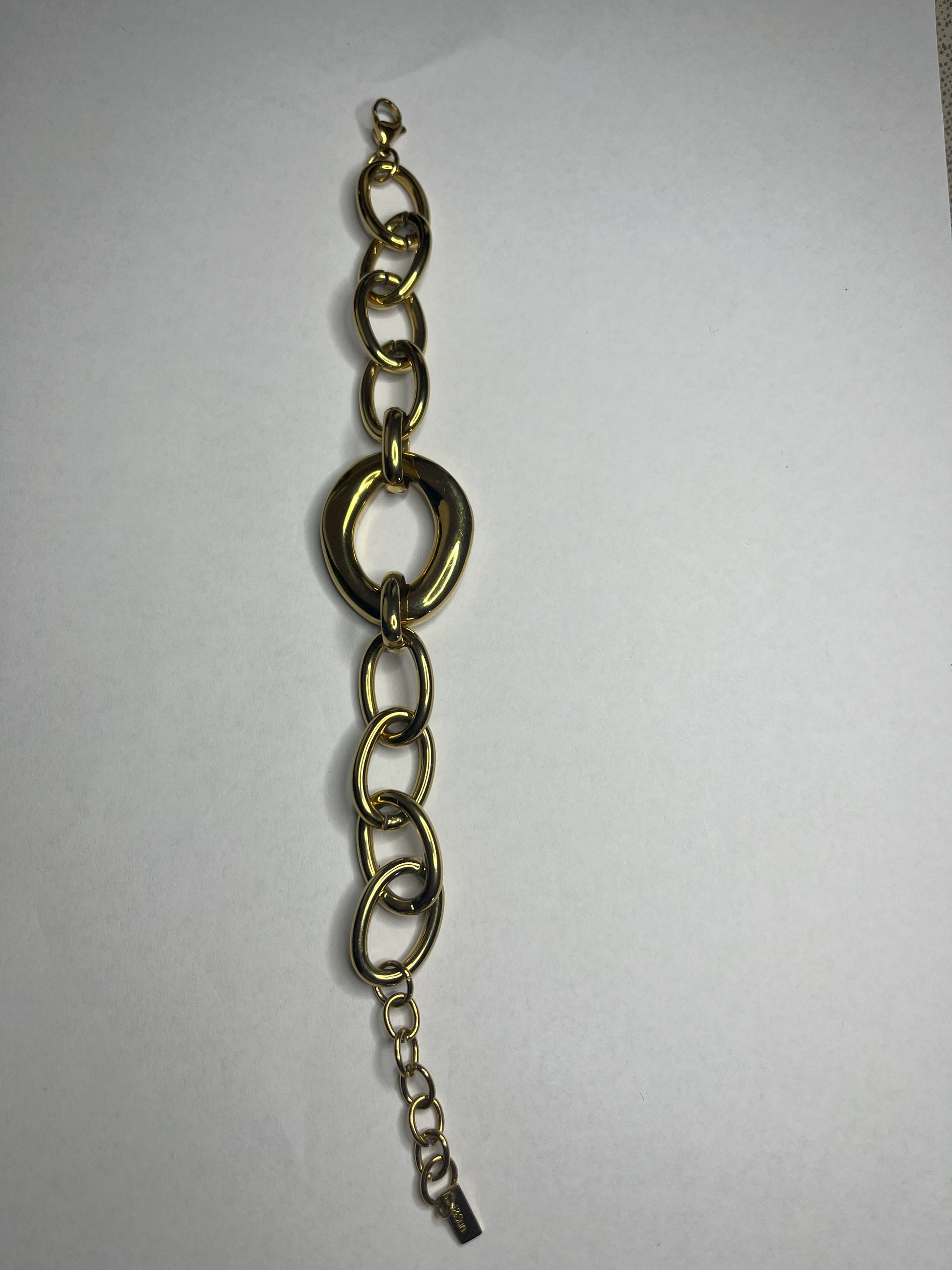 Bracciale Gold Evolution in acciaio 316L placcato oro con maglie graduate e anello centrale statement, su sfondo grigio neutro