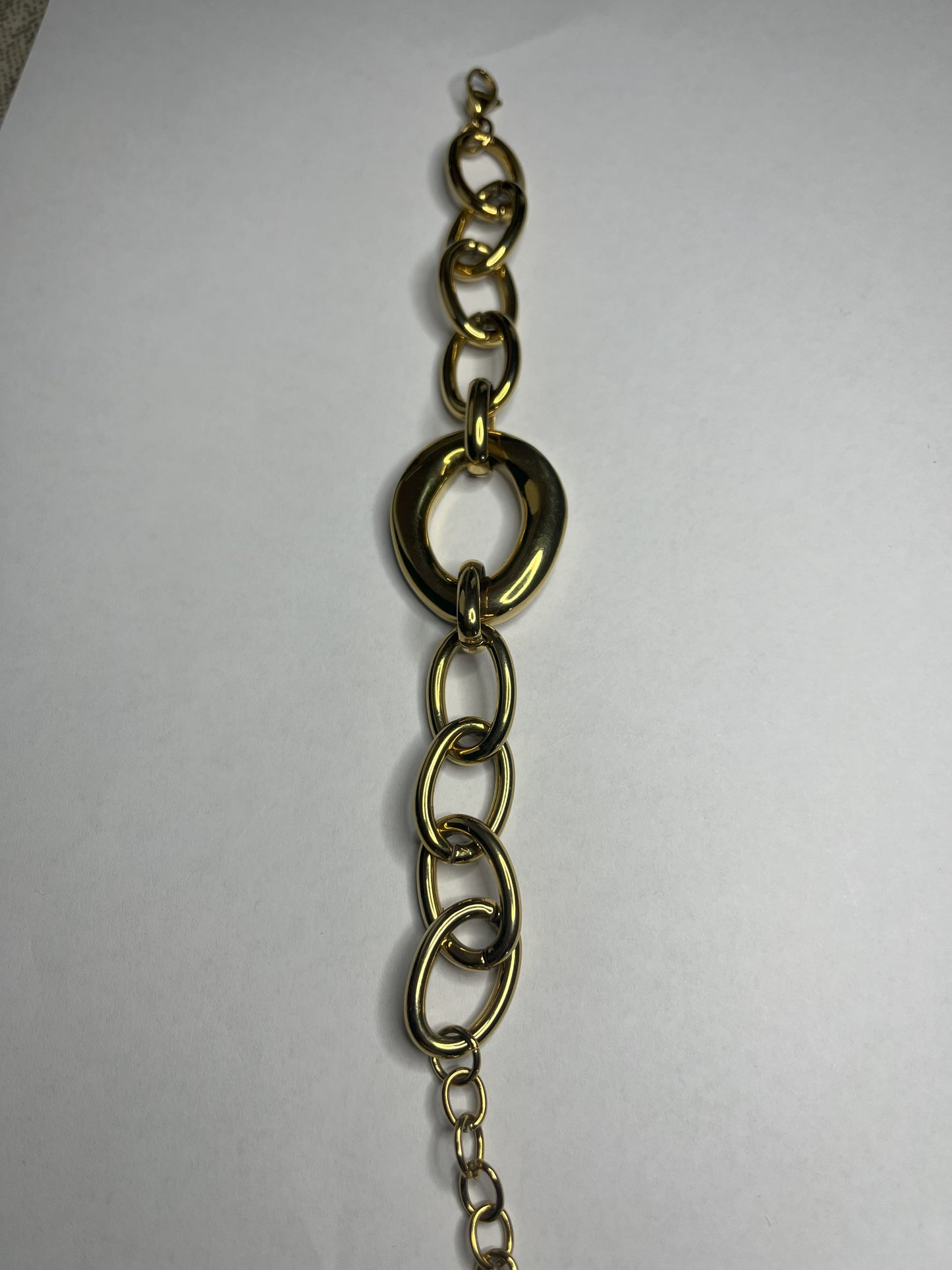 Bracciale Gold Evolution in acciaio 316L placcato oro con maglie graduate e anello centrale statement, su sfondo grigio neutro