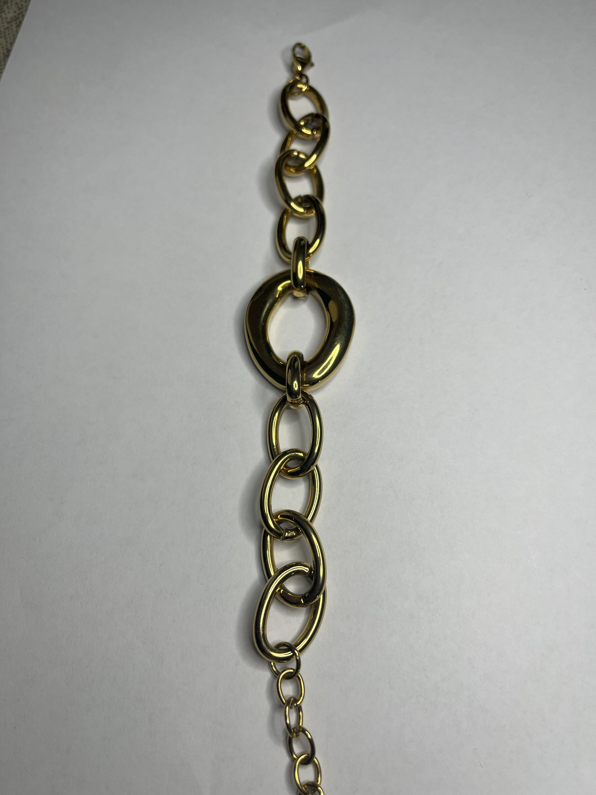Bracciale Gold Evolution in acciaio 316L placcato oro con maglie graduate e anello centrale statement, su sfondo grigio neutro