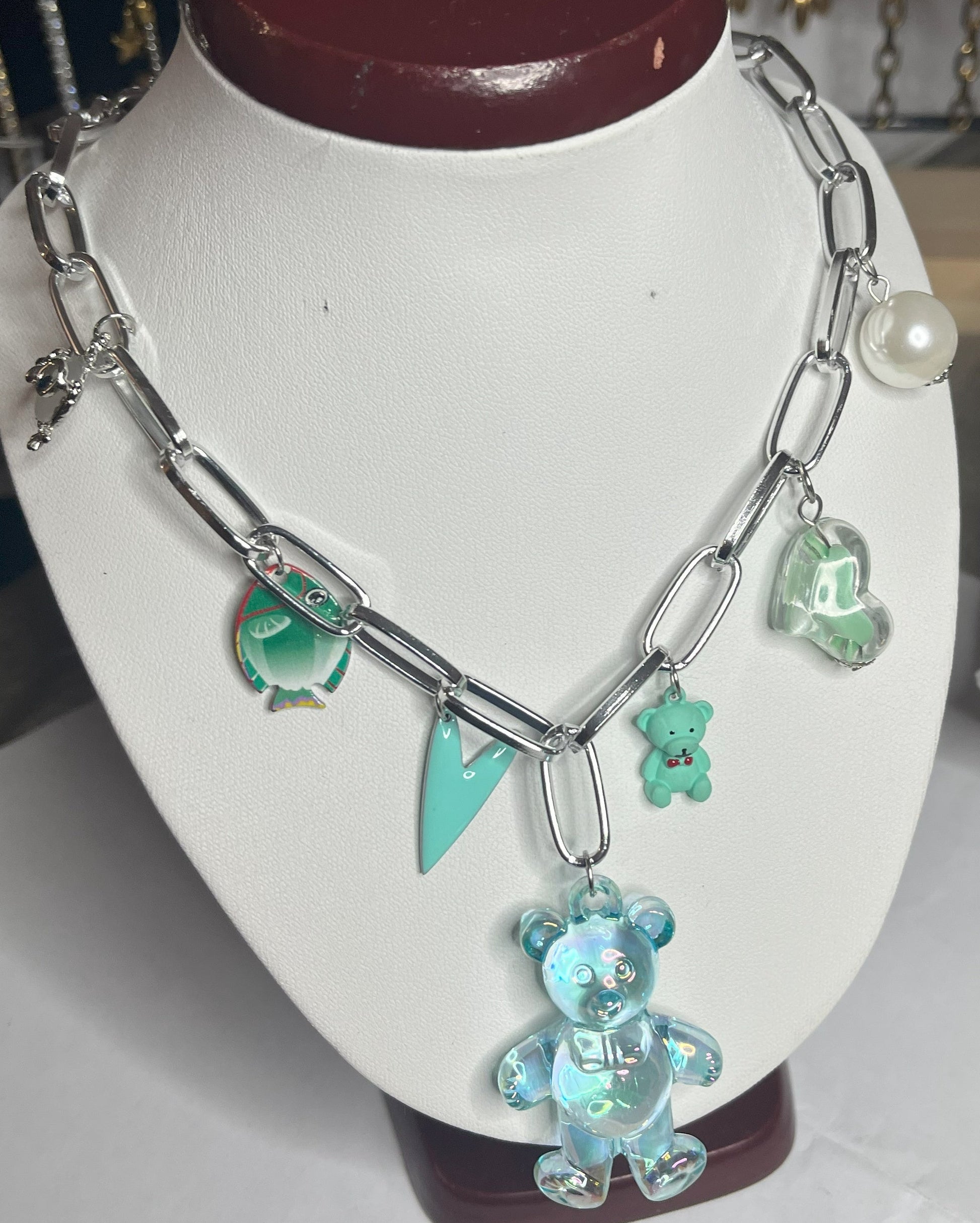 Collana chunky in alluminio trattato con orsetto turchese e pendenti verdi esposta su busto bianco