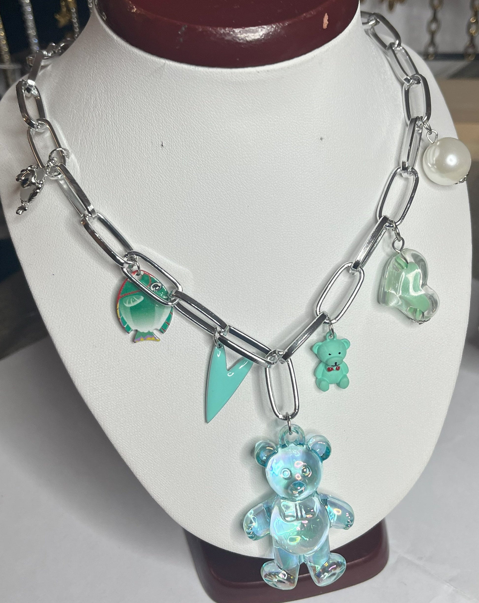 Collana chunky in alluminio trattato con orsetto turchese e pendenti verdi esposta su busto bianco