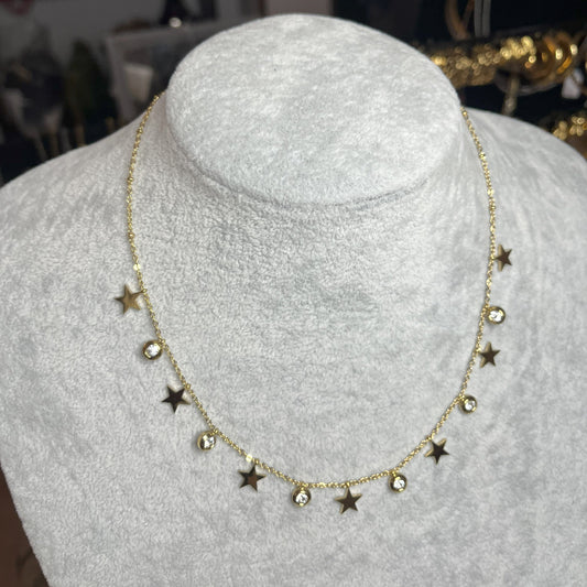 Collana Stellar Dreams in acciaio placcato oro con stelle dorate alternate a punti luce scintillanti su catena delicata, esposta su busto grigio