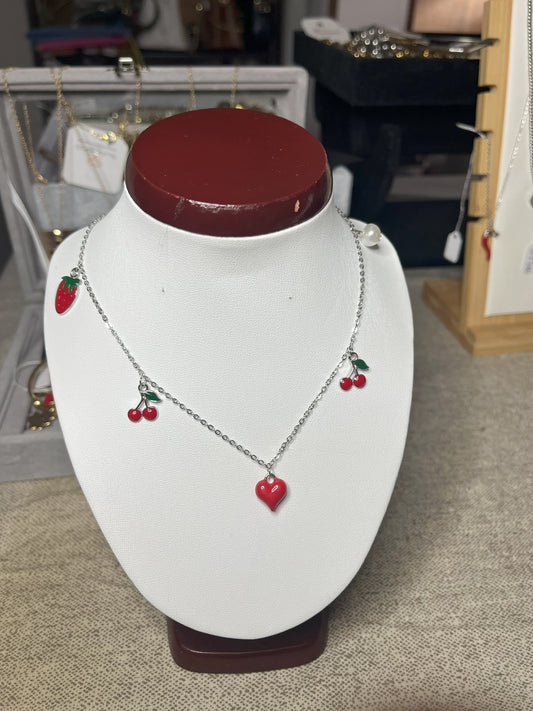 Collana Good Vibes con catena argentata e ciondoli colorati a forma di cuore, ciliegie e fragola, esposta su busto porta gioielli bianco