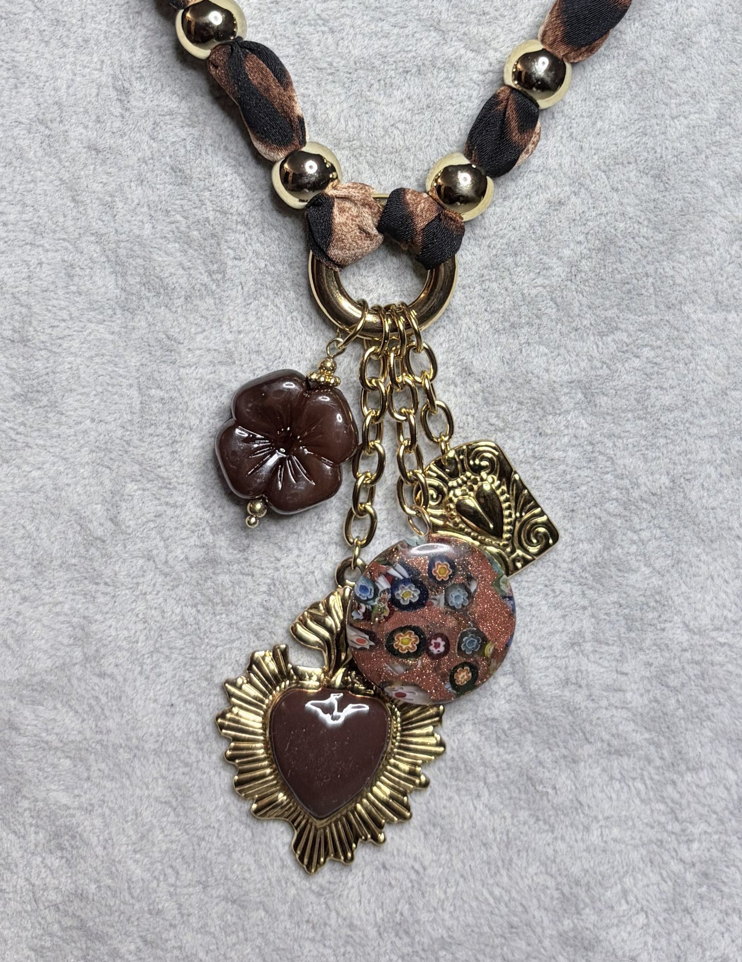 Dettaglio ciondoli collana leopardata: sacro cuore oro, millefiori e resina bordeaux