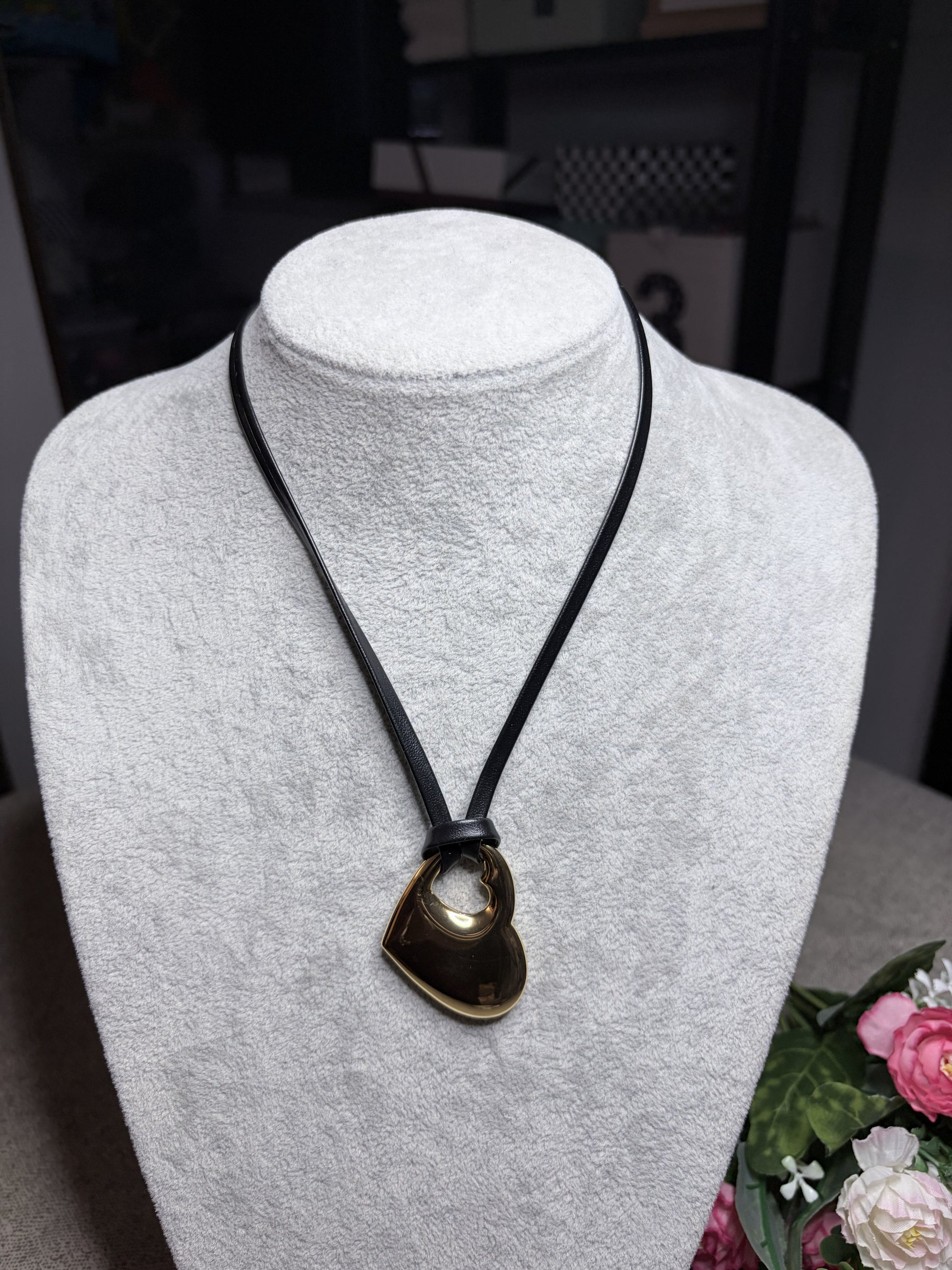 Collana cuore forato oro su cordino nero — vista frontale lunga su busto bianco