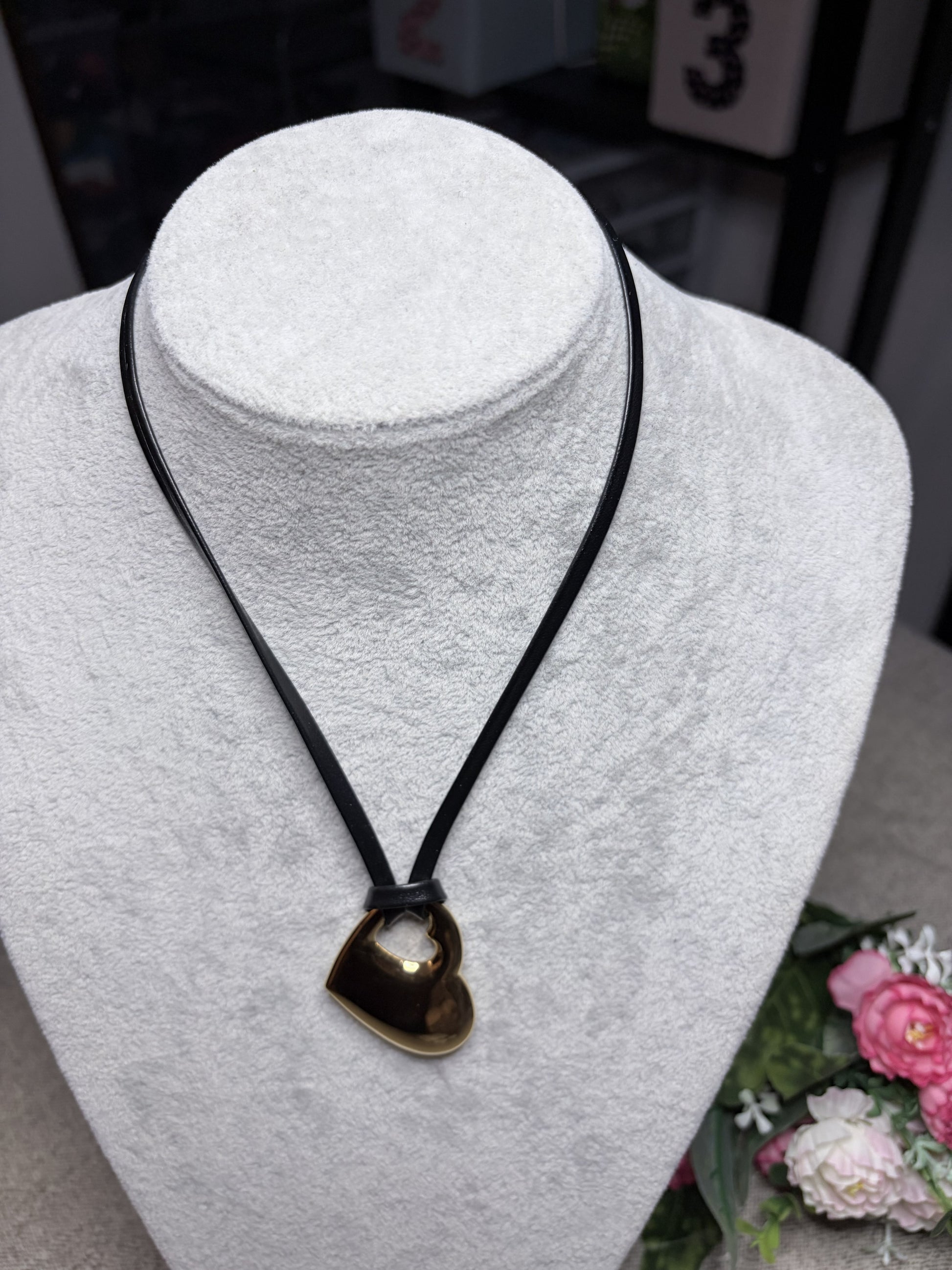 Collana cuore forato oro su cordino nero — vista frontale lunga su busto bianco