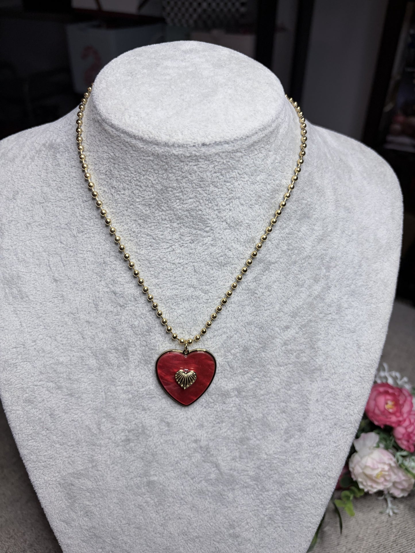 Collana cuore rosso smaltato con ciondolo dorato — vista frontale su busto bianco