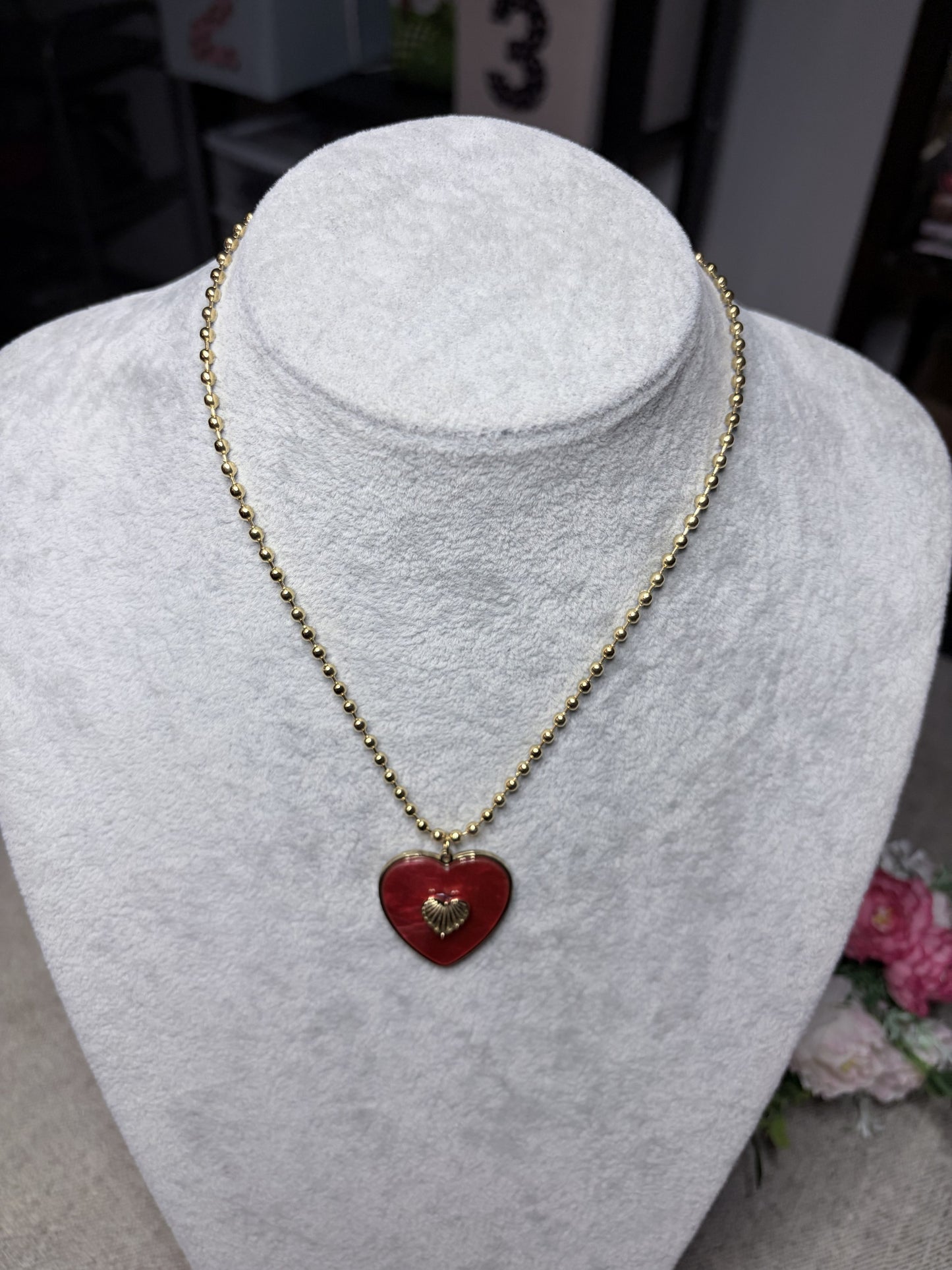 Collana cuore rosso smaltato con ciondolo dorato — vista frontale su busto bianco