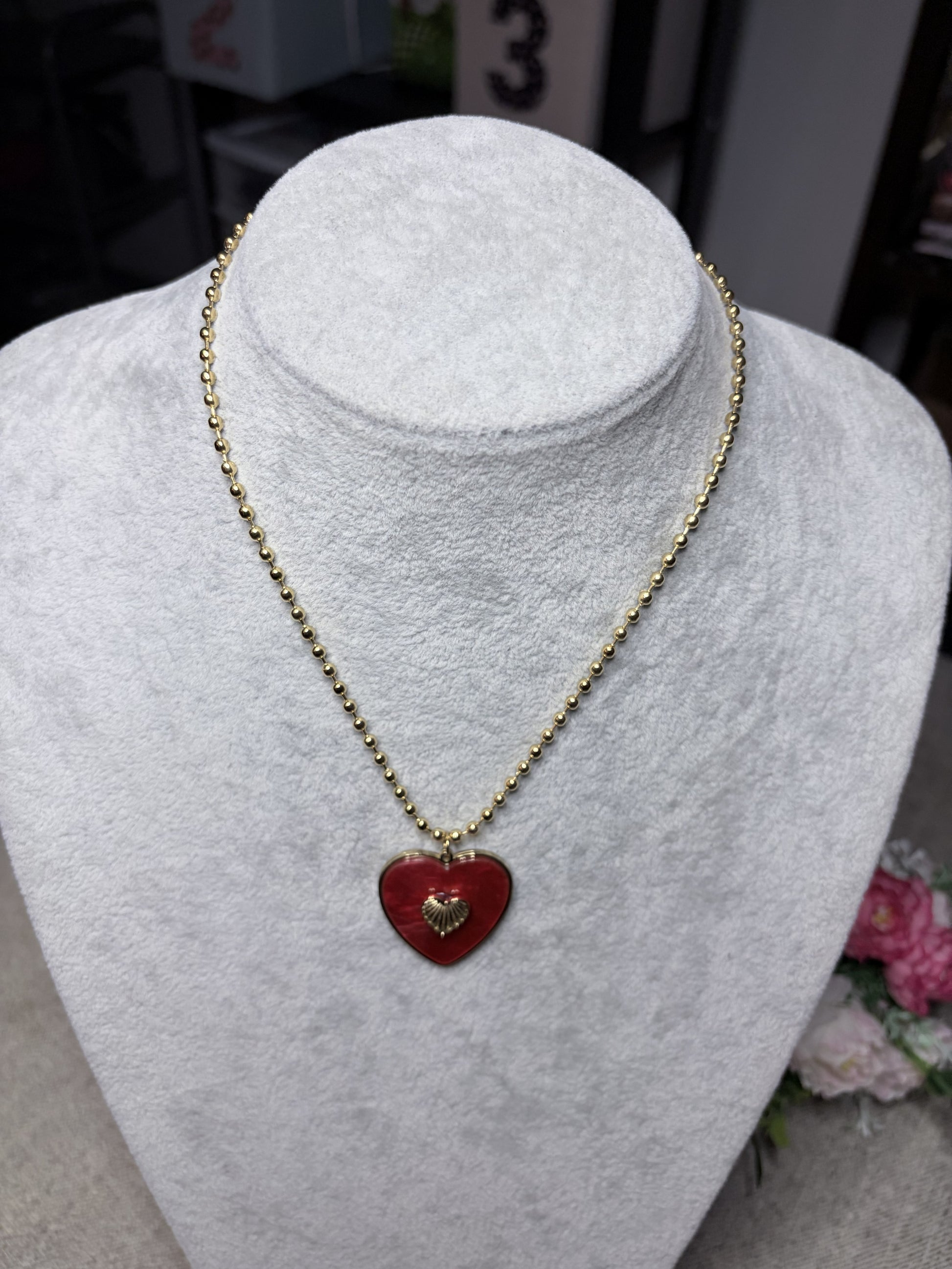 Collana cuore rosso smaltato con ciondolo dorato — vista frontale su busto bianco