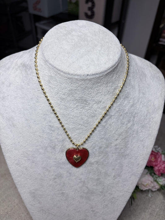Collana cuore rosso smaltato con ciondolo dorato — vista frontale su busto bianco