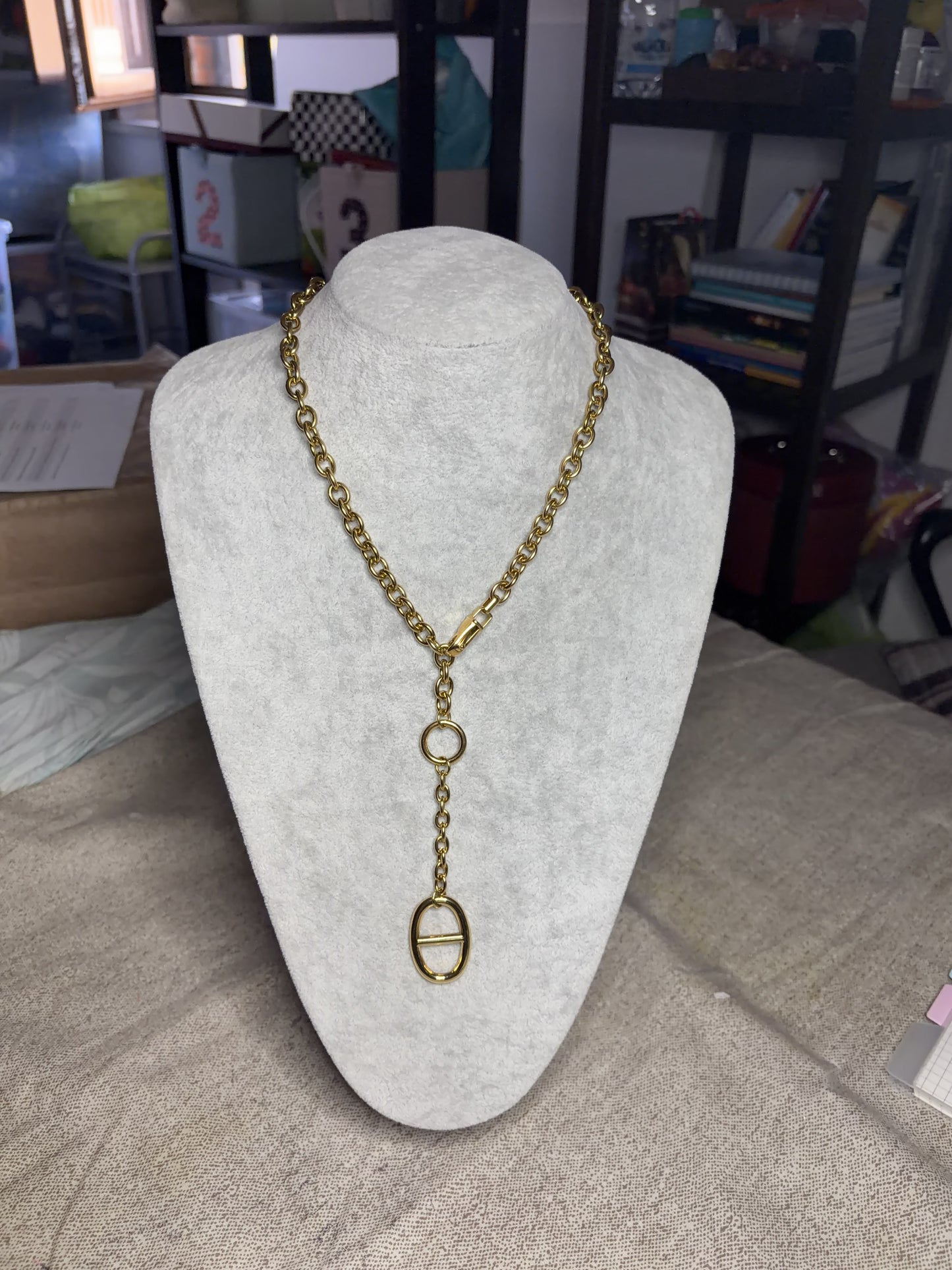 Collana lariat dorata — dettaglio ciondolo ovale con barra centrale