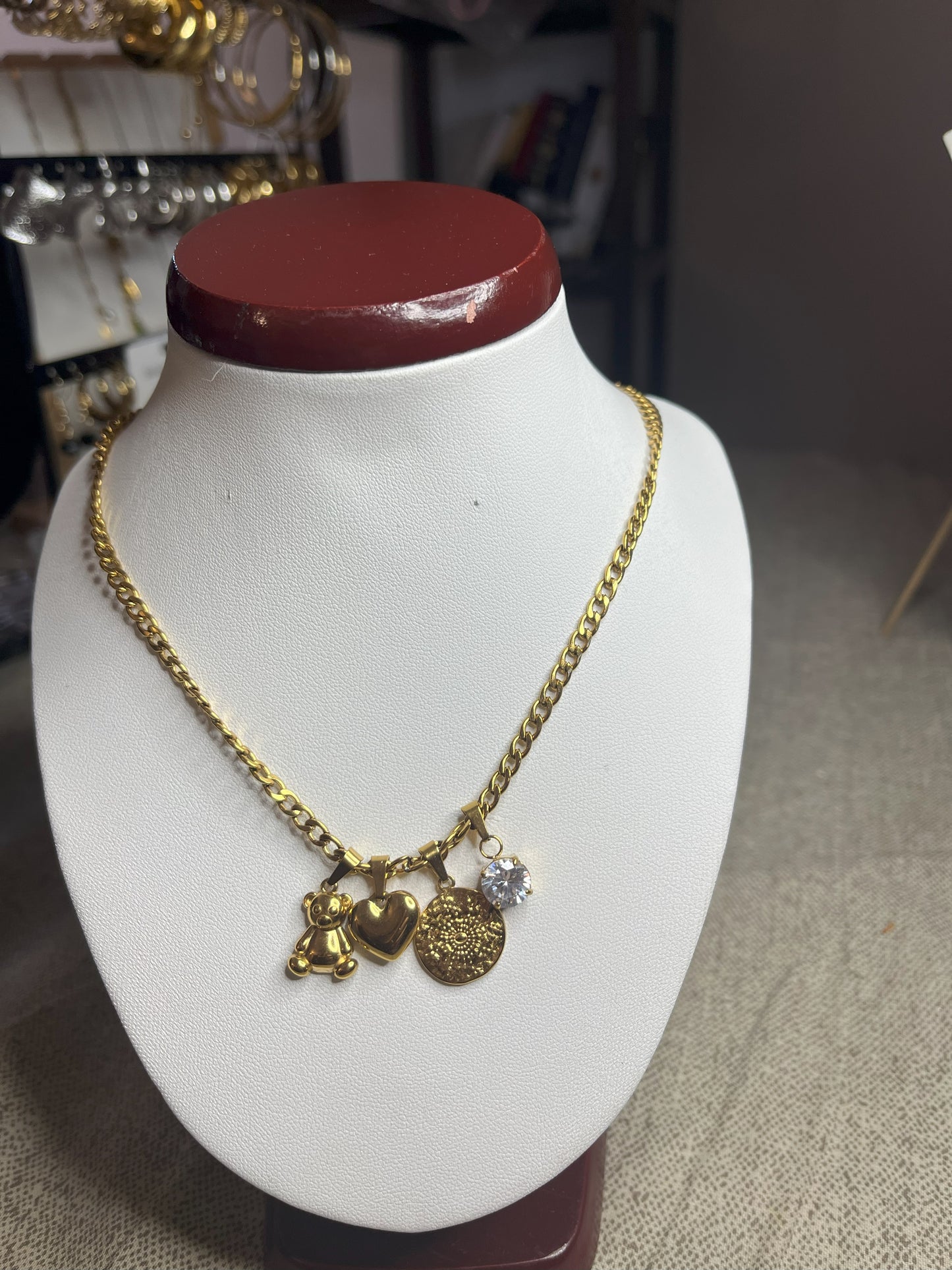 Collana Tesori Dorati in acciaio premium dorato con charm removibili: orsetto, cuore, medaglia decorativa e cristallo brillante su catena elegante. La collana è su espositore bianco