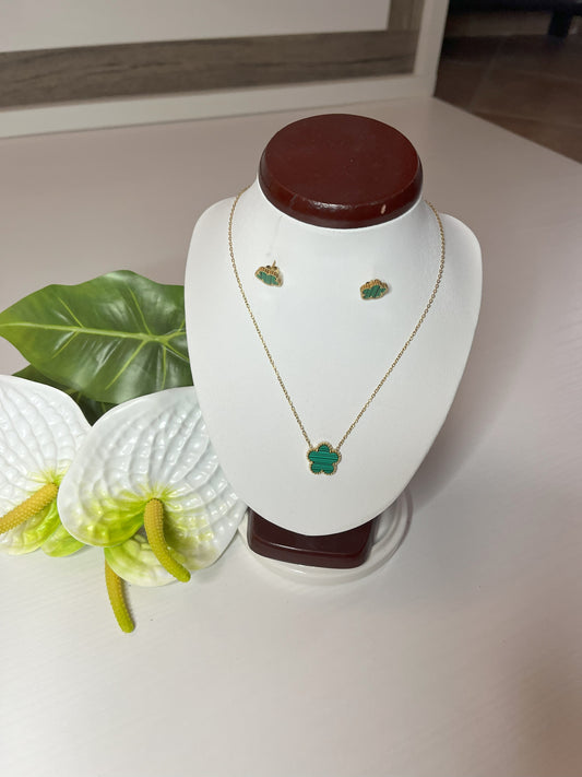 Set Elegance con collana e orecchini coordinati con pietre verdi smeraldo su catena dorata, esposto su busto bianco con decorazioni floreali