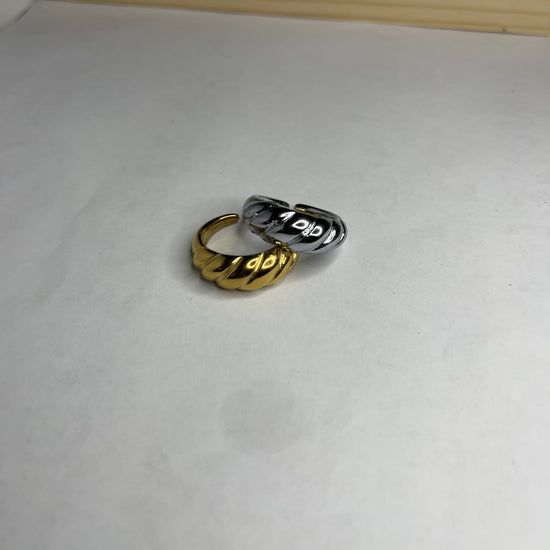 Anello con design intrecciato placcato oro, texture tridimensionale su sfondo neutro