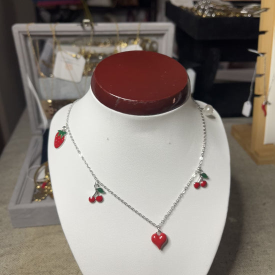 Collana Good Vibes con catena argentata e ciondoli colorati a forma di cuore, ciliegie e fragola, esposta su busto porta gioielli bianco