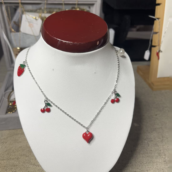 Collana Good Vibes con catena argentata e ciondoli colorati a forma di cuore, ciliegie e fragola, esposta su busto porta gioielli bianco