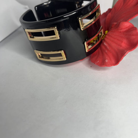 Bracciale rigido Golden Fusion nero con inserti geometrici placcati oro, design moderno ed elegante su sfondo bianco