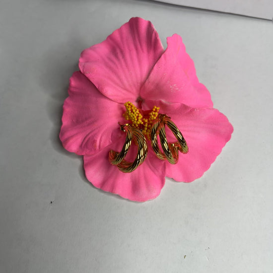 Orecchini Helix placcati oro premium con design a spirale tridimensionale, fotografati su petali di fiore rosa fucsia