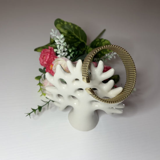 Braccialetto Cocò-G con elegante maglia dorata mesh e chiusura magnetica, esposto con decorazioni floreali rosa