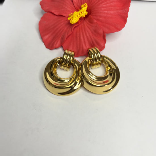 Orecchini dorati vintage anni 80 con design a cerchi concentrici su sfondo neutro