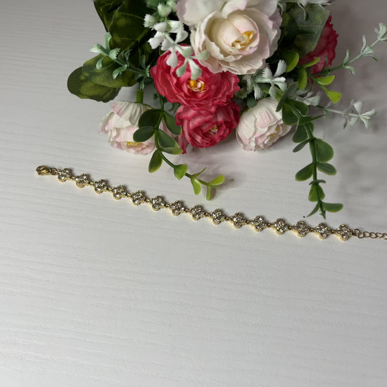  Braccialetto tennis placcato argento con quadrifogli portafortuna e cristalli scintillanti su sfondo bianco con foglie verdi