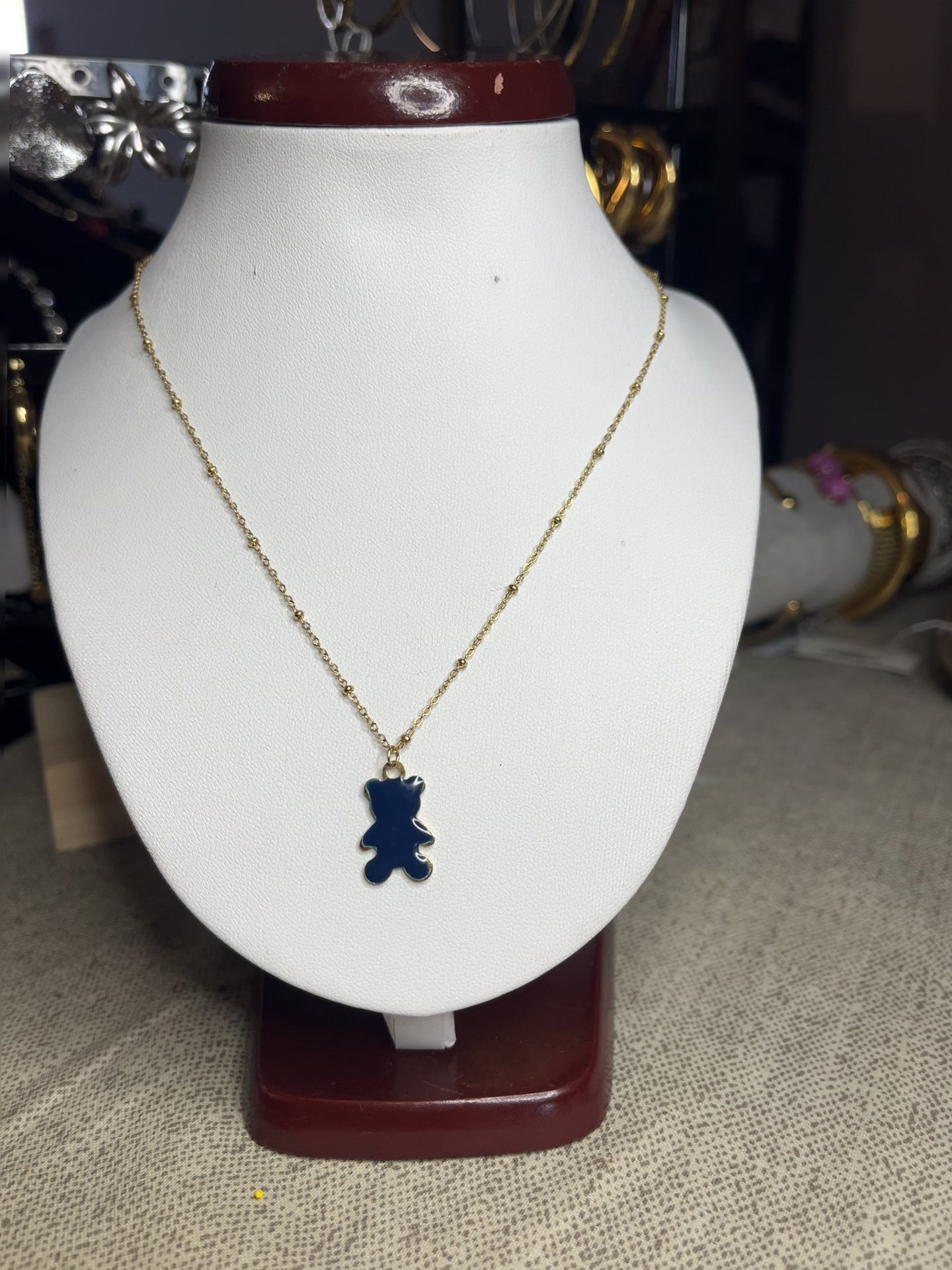 Collana Teddy con ciondolo orsetto blu in smalto e catena dorata, esposta su busto bianco