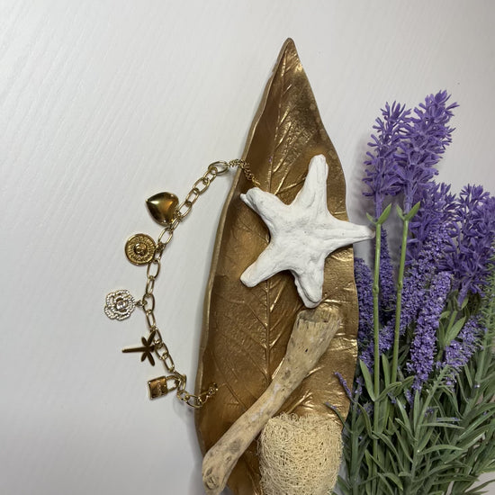 Braccialetto Multi-Charm in oro con ciondoli eleganti su sfondo neutro