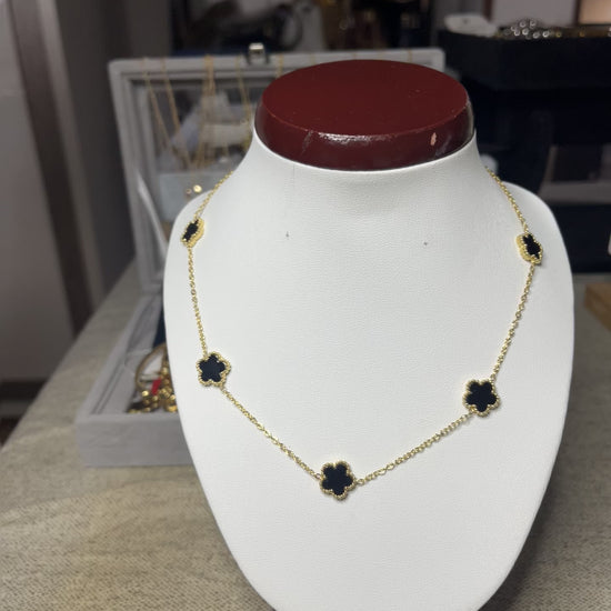 Collana Élégance Suprême in ottone dorato con cinque elementi floreali neri disposti simmetricamente, esposta su busto bianco, design elegante e raffinato stile italiano