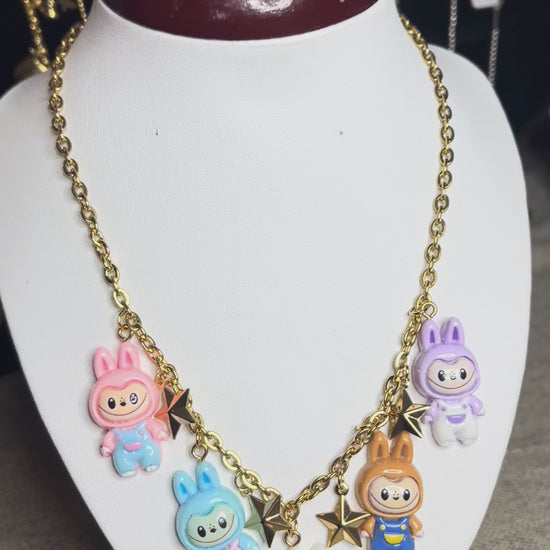 Collana con catena dorata e charms kawaii colorati a forma di personaggi cute, esposta su busto bianco