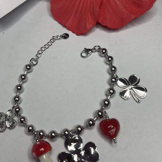 Braccialetto Giardino Magico in acciaio inox argentato con charms floreali, cuori rossi e perline colorate su sfondo grigio