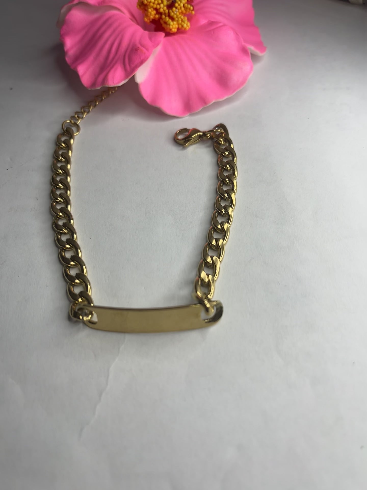 Bracciale Golden Thread sottile placcato oro con maglia fine delicata su sfondo grigio con petali rosa
