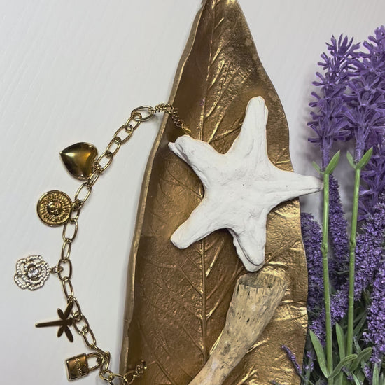 Braccialetto Multi-Charm in oro con ciondoli eleganti su sfondo neutro