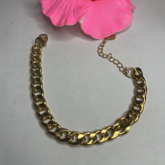 Bracciale Bold Chain placcato oro con maglie chunky grandi su sfondo grigio con petali rosa